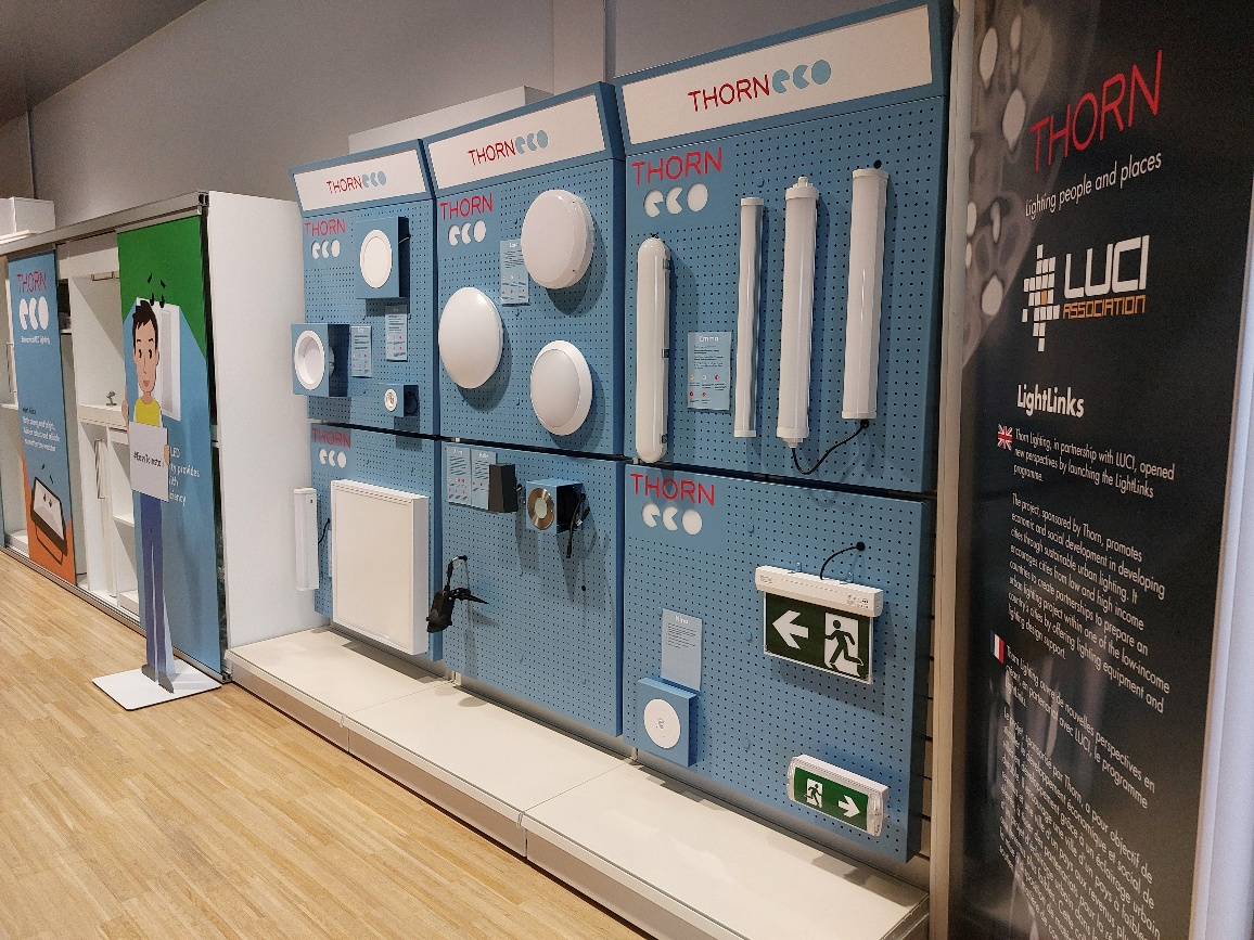 Thorn and Thorn Eco branded blue metal pegboard display panels mounted on a wall, showcasing various lighting products and fixtures