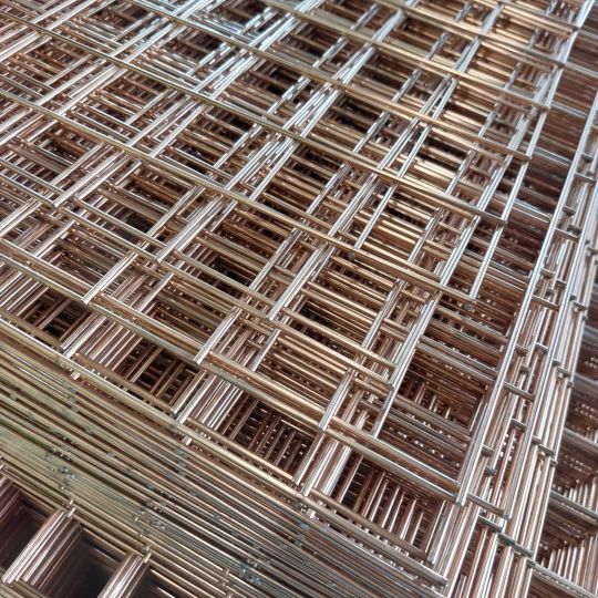 Stacked panels of bespoke wire mesh with a copper and silver welded grid pattern, photographed at an angle