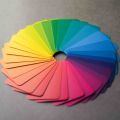 Colour swatches arranged in a circular colour wheel pattern on a grey surface, spanning the full spectrum