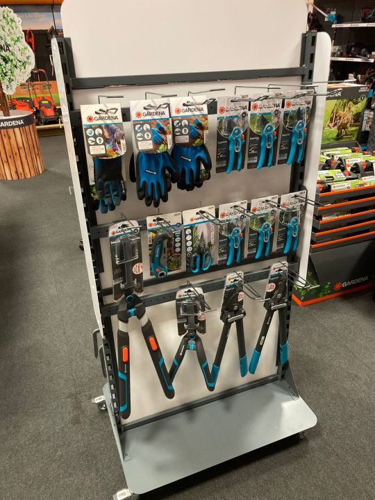 Gardena branded retail display stand featuring garden gloves, secateurs, scissors, and loppers in teal and black packaging
