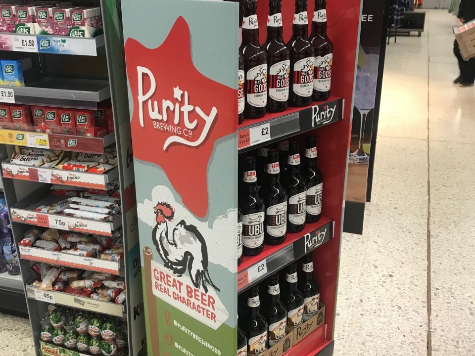 Wilkinson Sword garden tools retail POS display stand on a wooden pallet inside a warehouse, featuring hedge shears, rakes and pruners