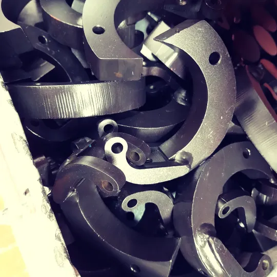 Hand lifting the lid of an empty dark metal box with silver clasp fastenings, placed on a light marble surface