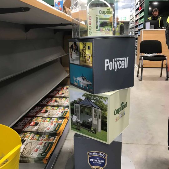 Gardena branded semi-permanent POS display stand holding spades, forks and rakes with teal handles at a trade exhibition