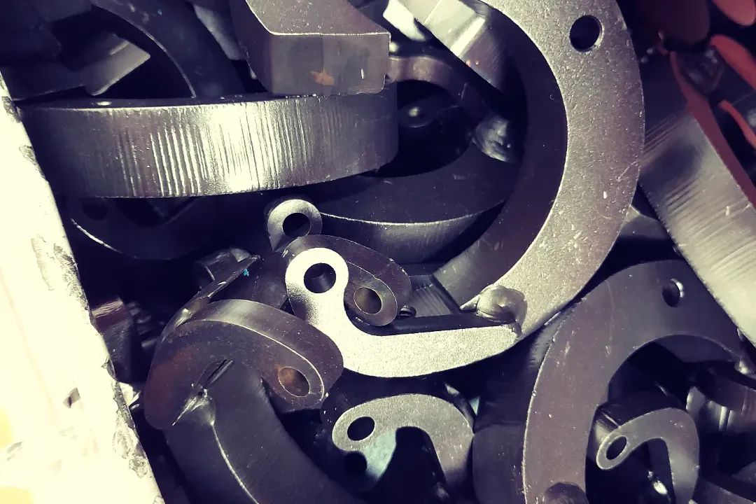 Dark grey metal box with silver clasp latches being held open by a hand, revealing an empty black interior, on a marble surface