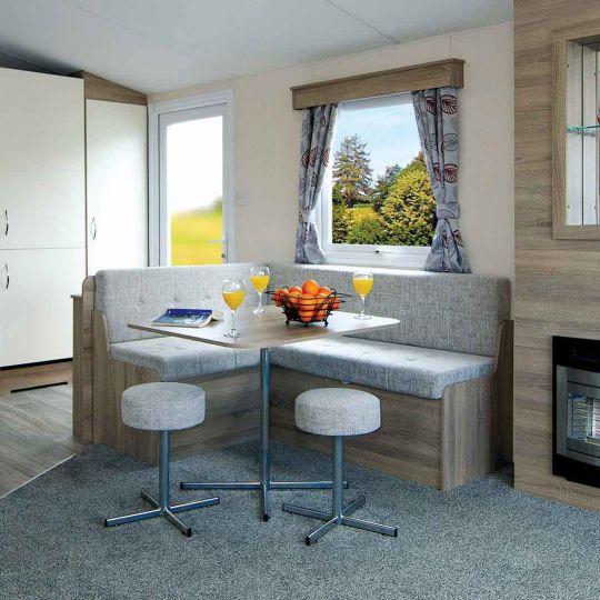 A lit Springdale touring caravan parked on open ground at dusk, with awning extended, steps down, and a cool box outside.