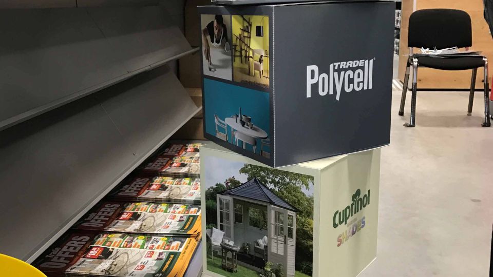 Gardena branded semi-permanent POS display stand holding spades, forks and rakes with teal handles at a trade exhibition